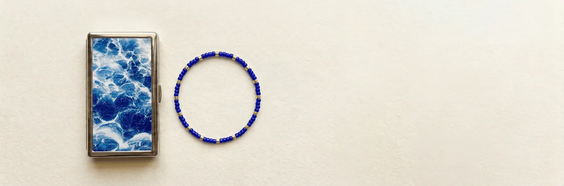 Tide steel wallet beside a matching blue beaded bracelet
